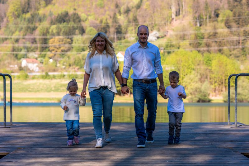 Familie geht Hand in Hand auf einem Steg in Richtung der Kamera