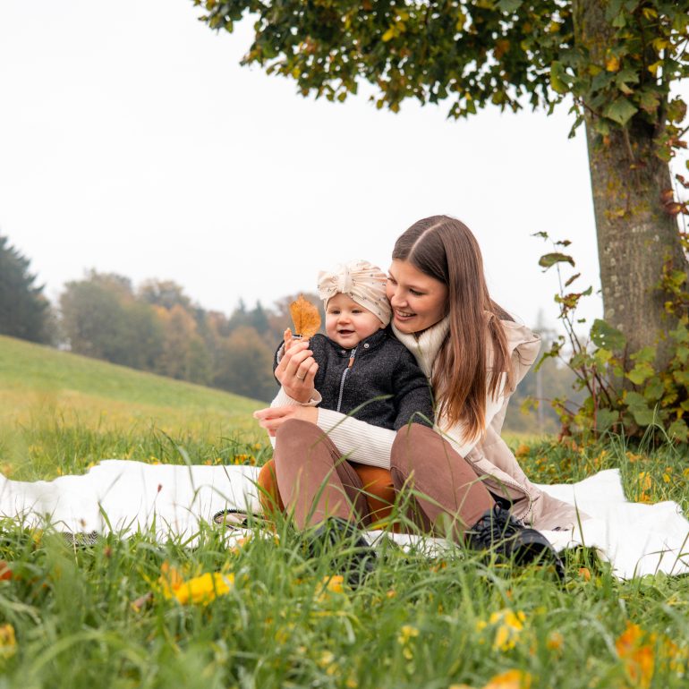 Mutter und Kind sitzen auf einer Decke und betrachten ein Blatt