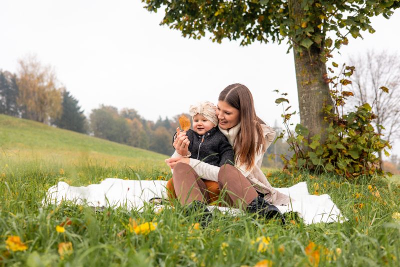 Mutter und Kind sitzen auf einer Decke und betrachten ein Blatt