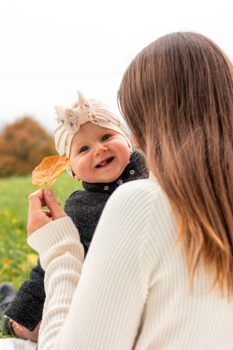 Kleines Baby wird von Mutter gehalten und strahlt in die Kamera.