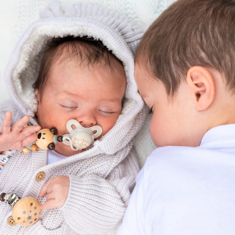 Baby und großer Bruder liegen Kopf an Kopf nebeneinander