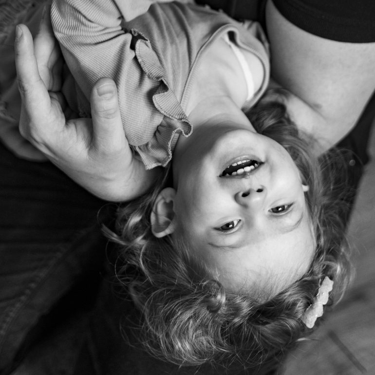 Lachendes kleines Kind, das vom Papa im Arm gehalten wird