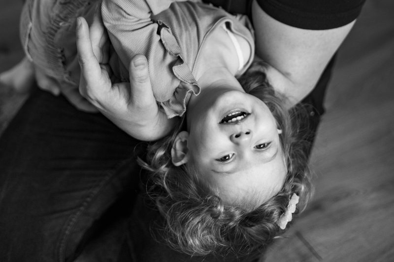 Lachendes kleines Kind, das vom Papa im Arm gehalten wird